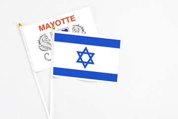 Israel and Mayotte stick flags on white background. High quality fabric, miniature national flag. Peaceful global concept.White floor for copy space.