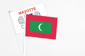 Maldives and Mayotte stick flags on white background. High quality fabric, miniature national flag. Peaceful global concept.White floor for copy space.