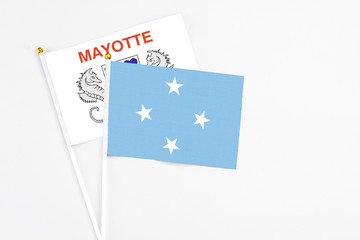 Micronesia and Mayotte stick flags on white background. High quality fabric, miniature national flag. Peaceful global concept.White floor for copy space.
