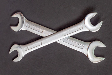 Crossed wrench symbol on black background. Two wrenches on top of each other. Service tool, repair concept.