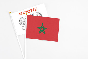 Morocco and Mayotte stick flags on white background. High quality fabric, miniature national flag. Peaceful global concept.White floor for copy space.