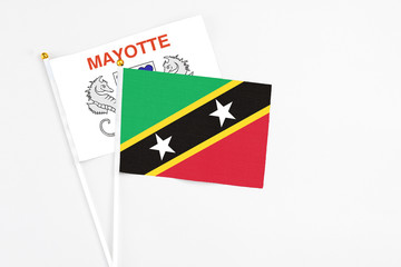 Saint Kitts And Nevis and Mayotte stick flags on white background. High quality fabric, miniature national flag. Peaceful global concept.White floor for copy space.
