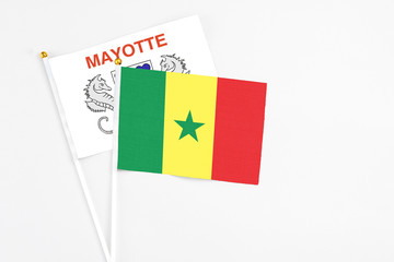 Senegal and Mayotte stick flags on white background. High quality fabric, miniature national flag. Peaceful global concept.White floor for copy space.