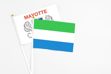 Sierra Leone and Mayotte stick flags on white background. High quality fabric, miniature national flag. Peaceful global concept.White floor for copy space.