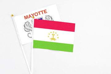Tajikistan and Mayotte stick flags on white background. High quality fabric, miniature national flag. Peaceful global concept.White floor for copy space.