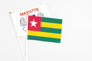 Togo and Mayotte stick flags on white background. High quality fabric, miniature national flag. Peaceful global concept.White floor for copy space.