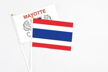 Thailand and Mayotte stick flags on white background. High quality fabric, miniature national flag. Peaceful global concept.White floor for copy space.