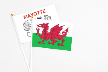 Wales and Mayotte stick flags on white background. High quality fabric, miniature national flag. Peaceful global concept.White floor for copy space.