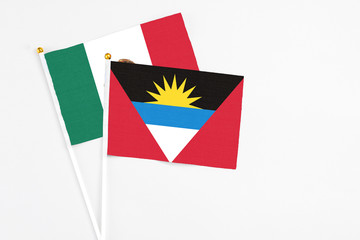 Antigua and Barbuda and Mexico stick flags on white background. High quality fabric, miniature national flag. Peaceful global concept.White floor for copy space.