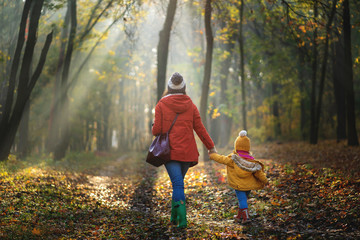Mother and her child on a wallk at autumn forest. Back view
