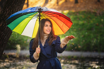 Woman wearing a coat outdoors. She used her hand to touch the rain.