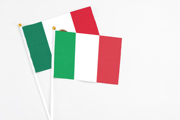 Italy and Mexico stick flags on white background. High quality fabric, miniature national flag. Peaceful global concept.White floor for copy space.