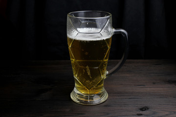 Glass of beer on a dark background on a wooden table