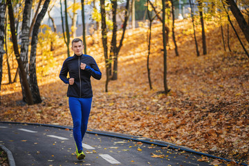 Young athletic man running at park during autumn morning