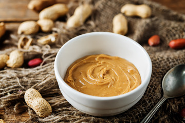 Peanut butter with peanuts on a dark wood background