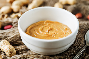 Peanut butter with peanuts on a dark wood background