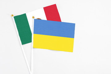Ukraine and Mexico stick flags on white background. High quality fabric, miniature national flag. Peaceful global concept.White floor for copy space.