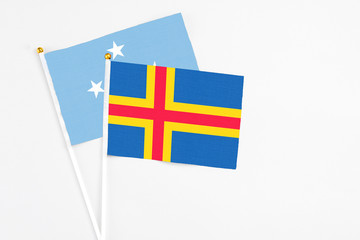 Aland Islands and Micronesia stick flags on white background. High quality fabric, miniature national flag. Peaceful global concept.White floor for copy space.