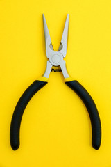 Single pliers tool with rubber handles for the master electrician on yellow background