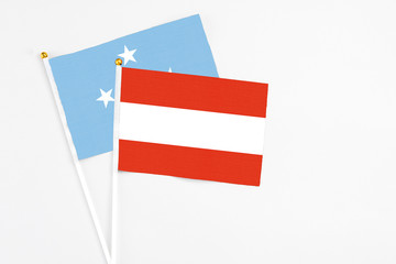 Austria and Micronesia stick flags on white background. High quality fabric, miniature national flag. Peaceful global concept.White floor for copy space.