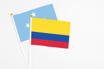 Colombia and Micronesia stick flags on white background. High quality fabric, miniature national flag. Peaceful global concept.White floor for copy space.