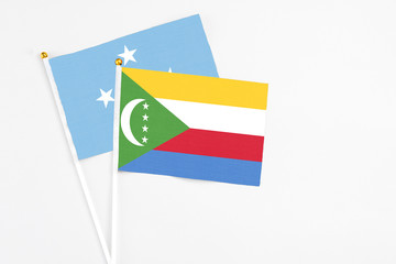 Comoros and Micronesia stick flags on white background. High quality fabric, miniature national flag. Peaceful global concept.White floor for copy space.