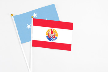 French Polynesia and Micronesia stick flags on white background. High quality fabric, miniature national flag. Peaceful global concept.White floor for copy space.