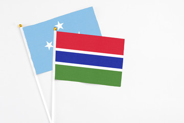 Gambia and Micronesia stick flags on white background. High quality fabric, miniature national flag. Peaceful global concept.White floor for copy space.