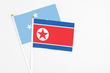 North Korea and Micronesia stick flags on white background. High quality fabric, miniature national flag. Peaceful global concept.White floor for copy space.