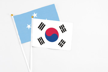South Korea and Micronesia stick flags on white background. High quality fabric, miniature national flag. Peaceful global concept.White floor for copy space.