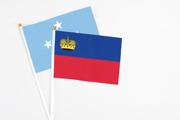 Liechtenstein and Micronesia stick flags on white background. High quality fabric, miniature national flag. Peaceful global concept.White floor for copy space.