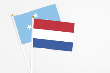 Netherlands and Micronesia stick flags on white background. High quality fabric, miniature national flag. Peaceful global concept.White floor for copy space.