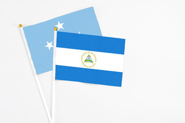 Nicaragua and Micronesia stick flags on white background. High quality fabric, miniature national flag. Peaceful global concept.White floor for copy space.