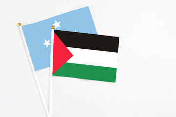Palestine and Micronesia stick flags on white background. High quality fabric, miniature national flag. Peaceful global concept.White floor for copy space.
