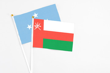Oman and Micronesia stick flags on white background. High quality fabric, miniature national flag. Peaceful global concept.White floor for copy space.