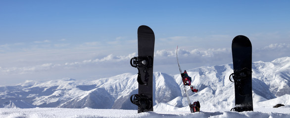 Three snowboards in snow near off-piste slope in sun day