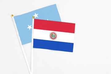 Paraguay and Micronesia stick flags on white background. High quality fabric, miniature national flag. Peaceful global concept.White floor for copy space.