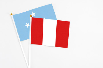 Peru and Micronesia stick flags on white background. High quality fabric, miniature national flag. Peaceful global concept.White floor for copy space.