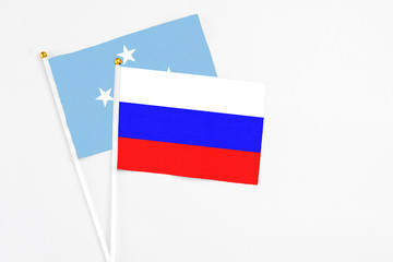 Russia and Micronesia stick flags on white background. High quality fabric, miniature national flag. Peaceful global concept.White floor for copy space.