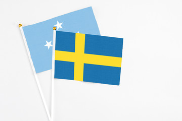 Sweden and Micronesia stick flags on white background. High quality fabric, miniature national flag. Peaceful global concept.White floor for copy space.