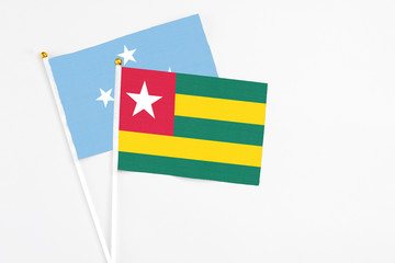 Togo and Micronesia stick flags on white background. High quality fabric, miniature national flag. Peaceful global concept.White floor for copy space.