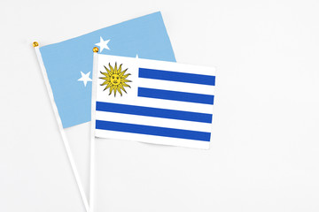 Uruguay and Micronesia stick flags on white background. High quality fabric, miniature national flag. Peaceful global concept.White floor for copy space.