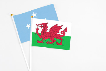 Wales and Micronesia stick flags on white background. High quality fabric, miniature national flag. Peaceful global concept.White floor for copy space.