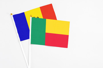 Benin and Moldova stick flags on white background. High quality fabric, miniature national flag. Peaceful global concept.White floor for copy space.