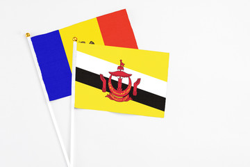 Brunei and Moldova stick flags on white background. High quality fabric, miniature national flag. Peaceful global concept.White floor for copy space.