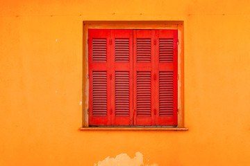Red shutters with yellow wall. Exterior of red shutters and yellow wall. Background of yellow wall with red shutters. Red and yellow in exterior of the building. Copy space