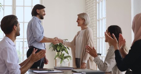Happy older female employee get promoted rewarded handshaking boss