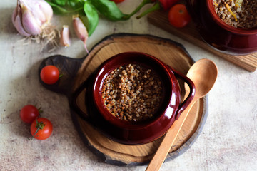 Appetizing buckwheat porridge with meat in clay pots on a beautiful wooden Board with a wooden spoon
