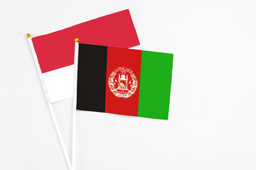 Afghanistan and Monaco stick flags on white background. High quality fabric, miniature national flag. Peaceful global concept.White floor for copy space.