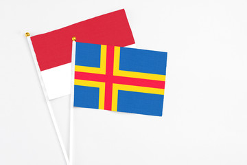 Aland Islands and Monaco stick flags on white background. High quality fabric, miniature national flag. Peaceful global concept.White floor for copy space.